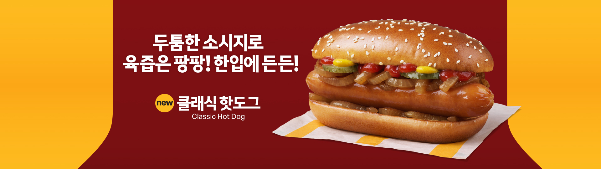 ‘두툼한 소시지로 육즙은 팡팡! 한입에 든든!’ 문구와 함께, 소시지, 볶은 양파, 피클, 케첩, 머스터드가 들어간 참깨 번 핫도그 이미지. 제품명은 ‘new 클래식 핫도그’