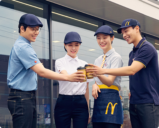 맥도날드 매장에서 직원들이 환하게 웃으며 손을 흔들면서 포즈를 취하고 있는 사진