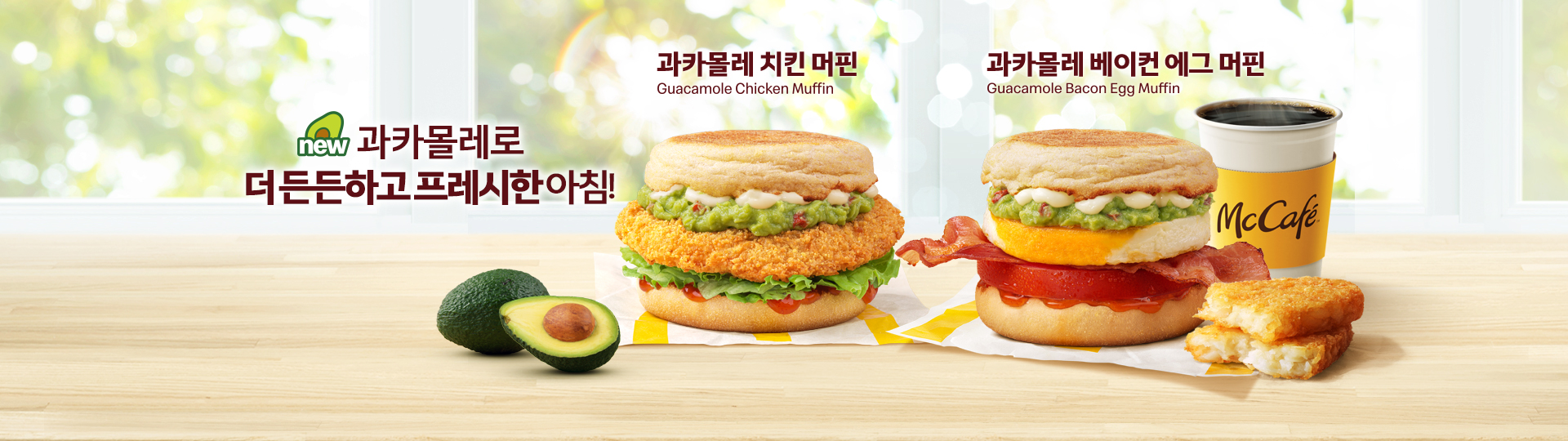 밝은 창가 배경의 테이블 위에 “new 과카몰레로 더 든든하고 프레시한 아침!”이라는 문구와 함께 맥도날드 아침 신메뉴 2종이 놓여 있다.   왼쪽에는 ‘과카몰레 치킨 머핀’이 배치되어 있으며, 잉글리시 머핀 사이에 바삭하게 튀긴 치킨 패티, 초록빛 과카몰레 소스, 양상추, 토마토가 층층이 들어가 있다. 제품 앞에는 통 아보카도와 반으로 자른 아보카도가 함께 놓여 있다.  오른쪽에는 ‘과카몰레 베이컨 에그 머핀’이 놓여 있으며, 잉글리시 머핀 사이에 과카몰레 소스, 계란 패티, 바삭한 베이컨, 토마토가 들어가 있으며, 제품 옆에는 커피와 해시브라운이 함께 배치되어 있다.