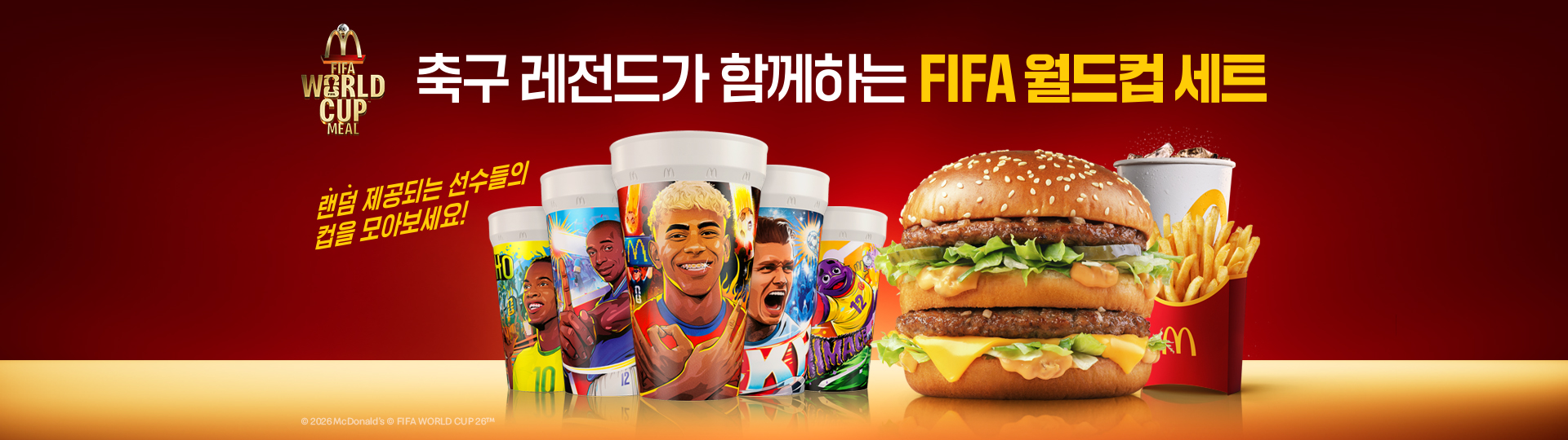 붉은 배경의 맥도날드 FIFA 월드컵 밀 배너.  상단에는 ‘축구 레전드가 함께하는 FIFA 월드컵 세트’ 문구가 있고, 중앙에는 랜덤 제공되는 축구 선수 일러스트 디자인 컵 여러 개가 배치되어 있습니다.  컵의 오른쪽에는 빅맥, 후렌치 후라이, 음료가 함께 놓여 있으며, 컵의 왼쪽에는 ‘랜덤 제공되는 선수들의 컵을 모아보세요!’라는 안내 문구가 보입니다.